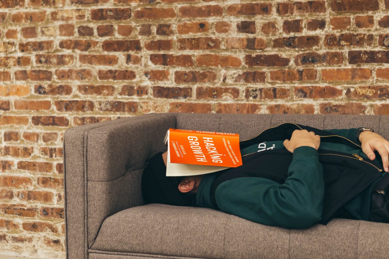person lying on couch with book over thier head